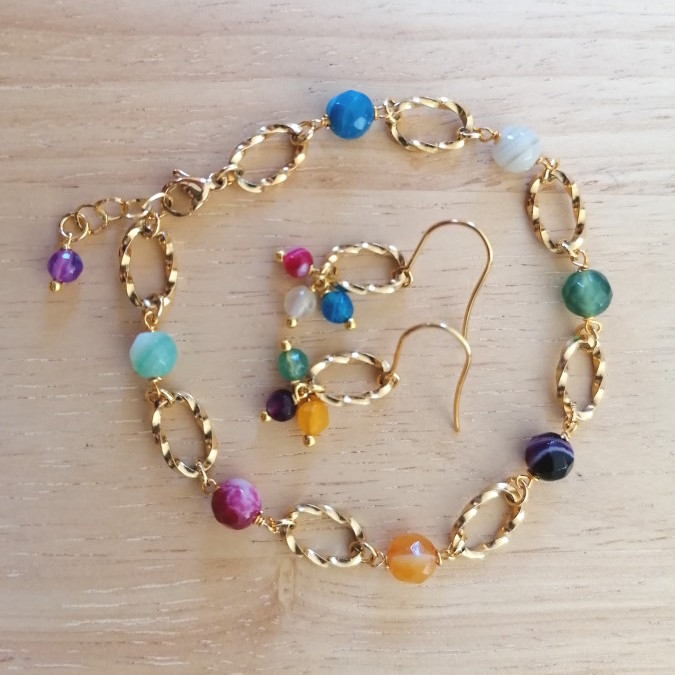 Armbånd og øreringe, Farverige perler og små gyldne detaljer samler armbånd og øreringe i et livligt sæt med en varm og personlig stemning.