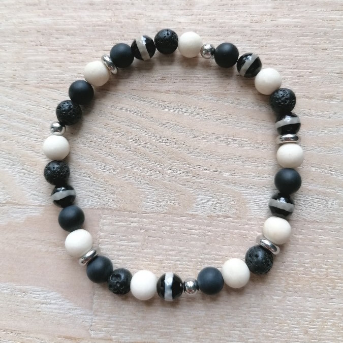 Elastikarmbånd, Sorte og lyse perler ligger i en rolig rytme omkring håndleddet – et enkelt armbånd med tydelig grafisk kontrast.
